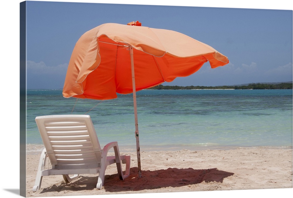 Close-up of relaxing chair with parasol umbrella on beach.