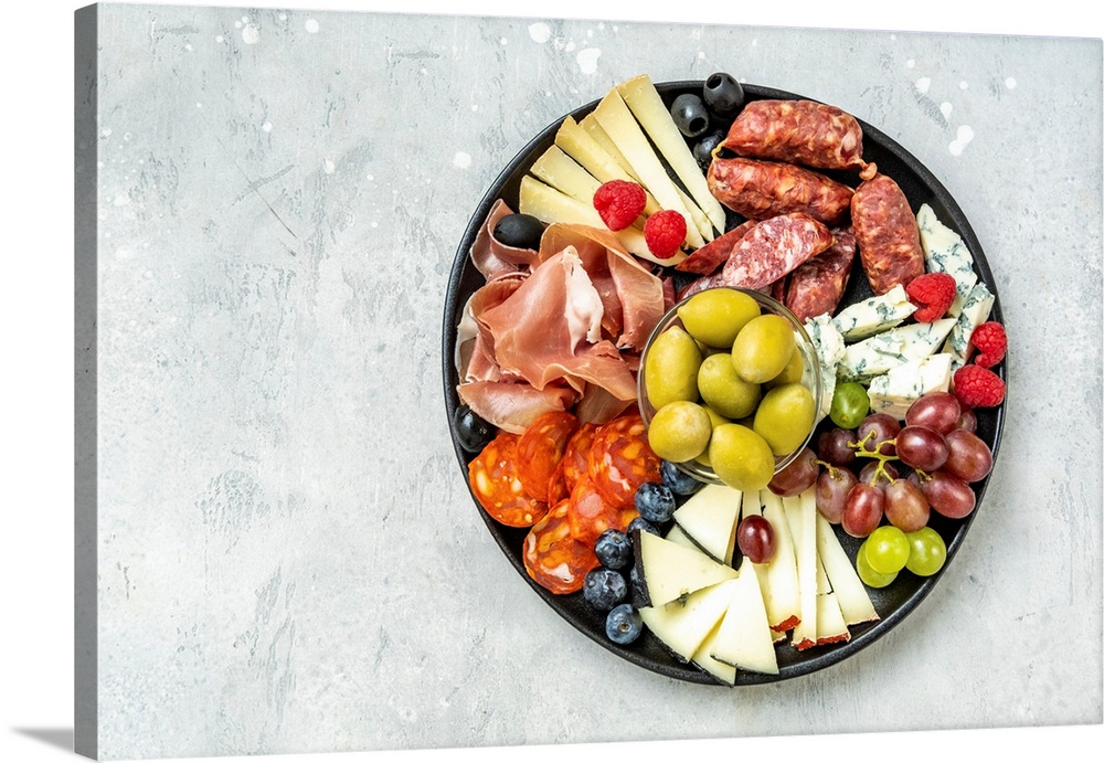 Charcuterie board with Italian salami, prosciutto, various cheeses, and olives. Grapes, snacks in the restaurant for an ap...