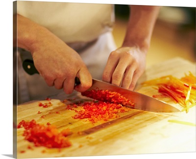 Chef mincing bell peppers with knife