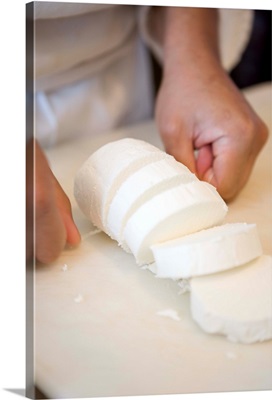 Chef slicing goat cheese with string