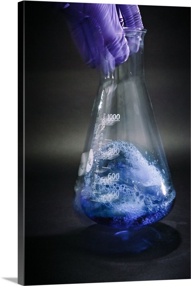 Male scientist shaking a blue liquid inside an Erlenmeyer flask.