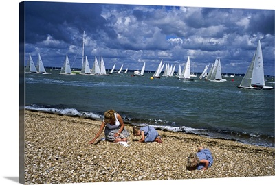 Children playing on beach with yachts in background, Cowes Week Regatta