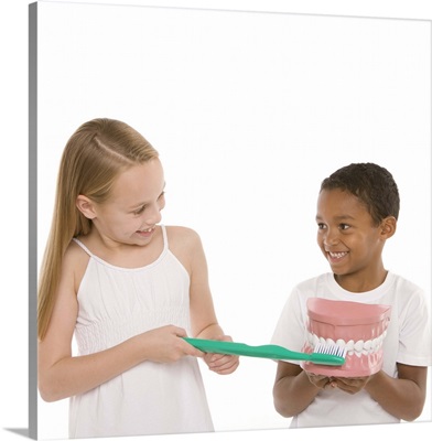 Children with a model set of teeth and oversized toothbrush