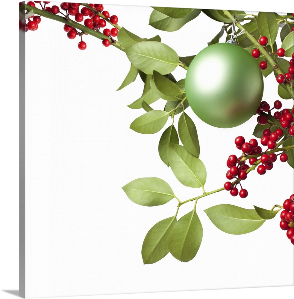 Christmas decoration with red holly berries, leaves and a green christmas ball, isolated on white background.