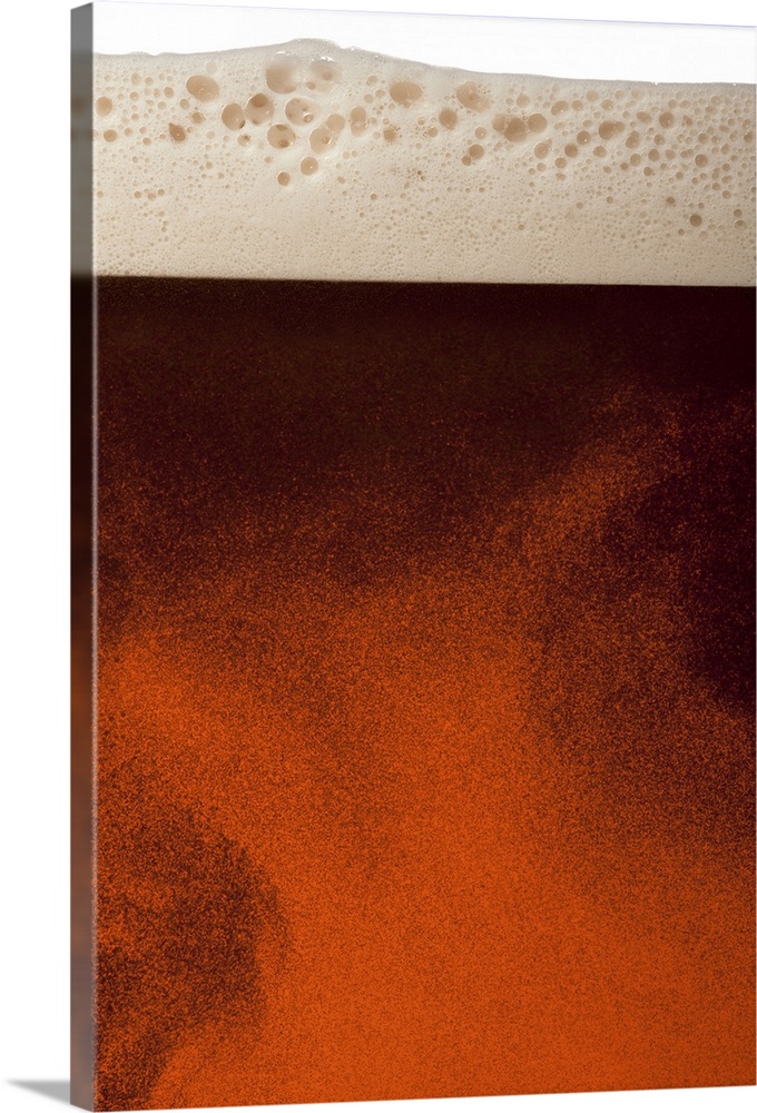 Close up image of amber colored beer with frothy head, swirling bubbles and copy space