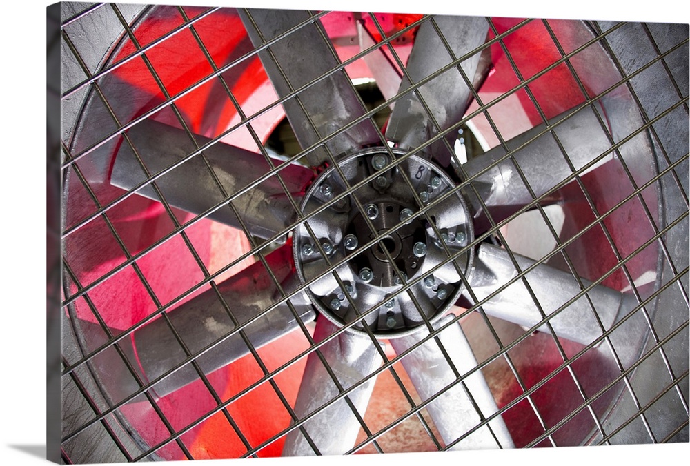 Close-up of an industrial ventilation fan with red hues lighting up the back.