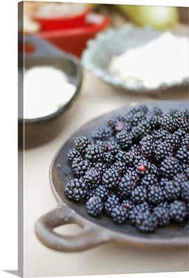 Close up of bowl of blackberries on a table with bowls of cheese and bread.