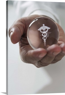 Close up of man holding clear ball with Caduceus symbol