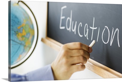 Close-up of man's hand writing ''education'' on blackboard