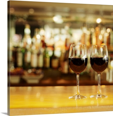 Close-up of two glasses of red wine on bar counter