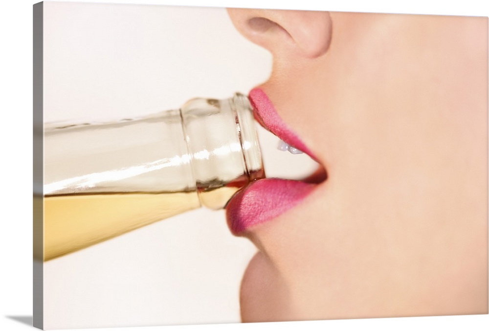 This picture is taken closely of a woman's mouth as she begins to take a sip from a bottled drink.