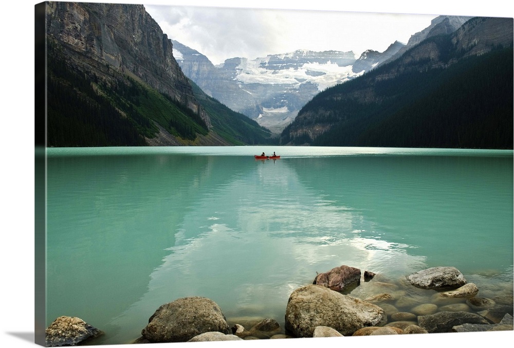 Pleasure boaters row on the placid turquoise waters of Lake Louise, Banff National Park, Canada, on a cloudy summer day. V...