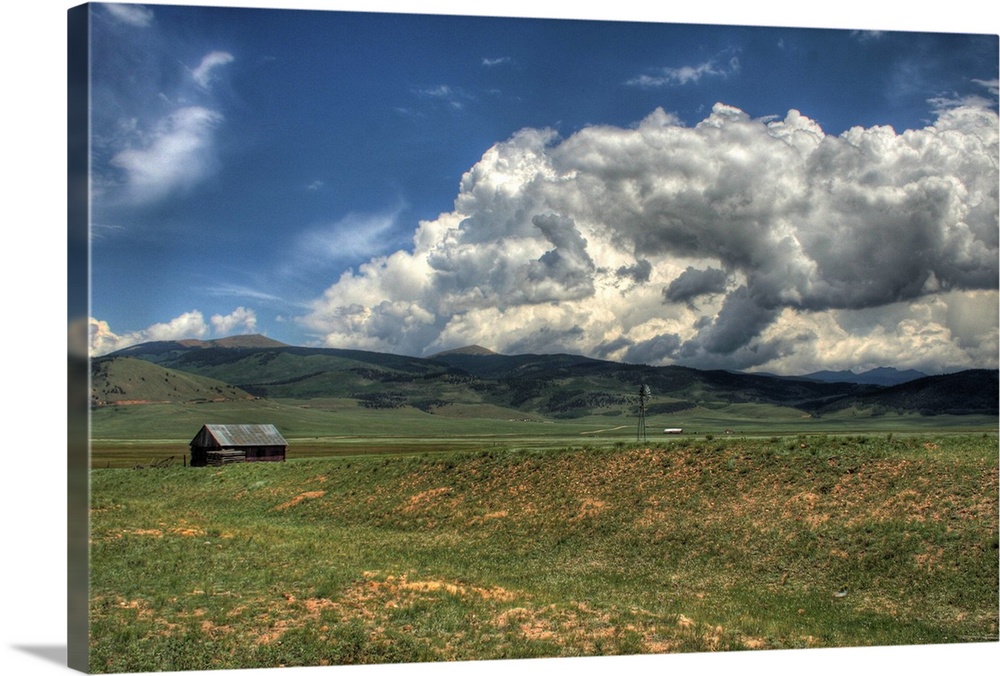 A HDR shot of a high plains farm near South Park, CO with massive clouds rolling over the mountains in the background.