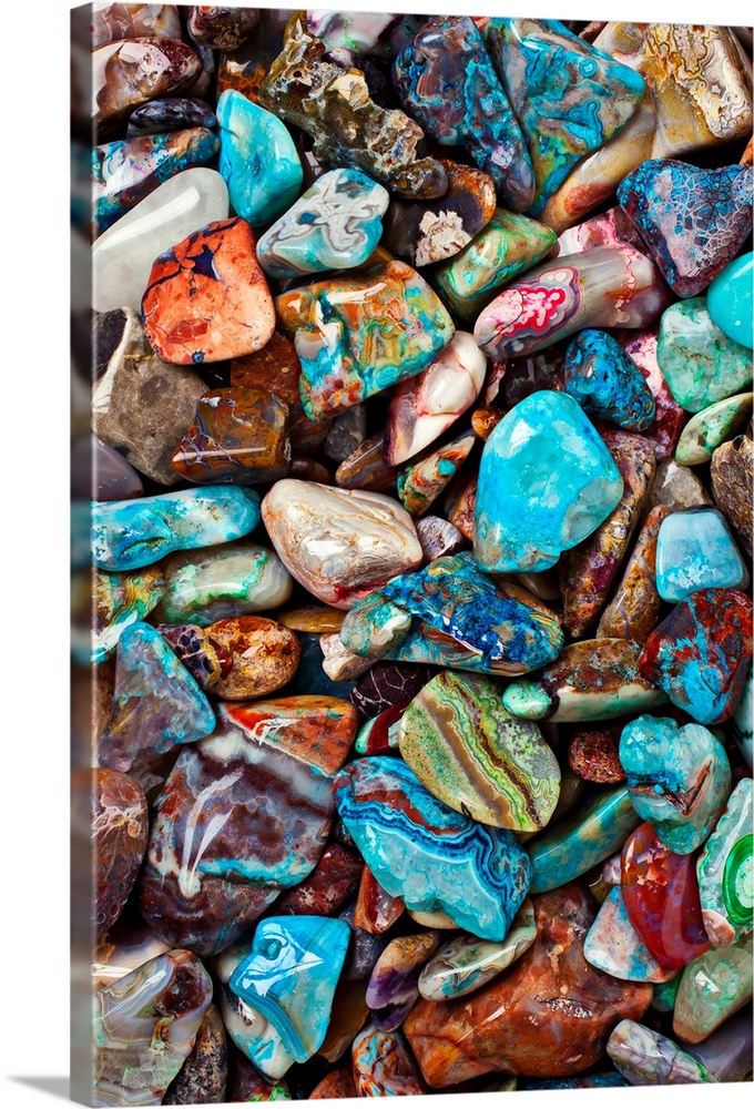Large close-up photograph focuses on an abundance of vibrantly tinted smooth rocks as they sit next to and on top of each ...