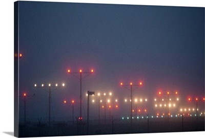 Colorful fogbound landing lights guide airplanes to runway.