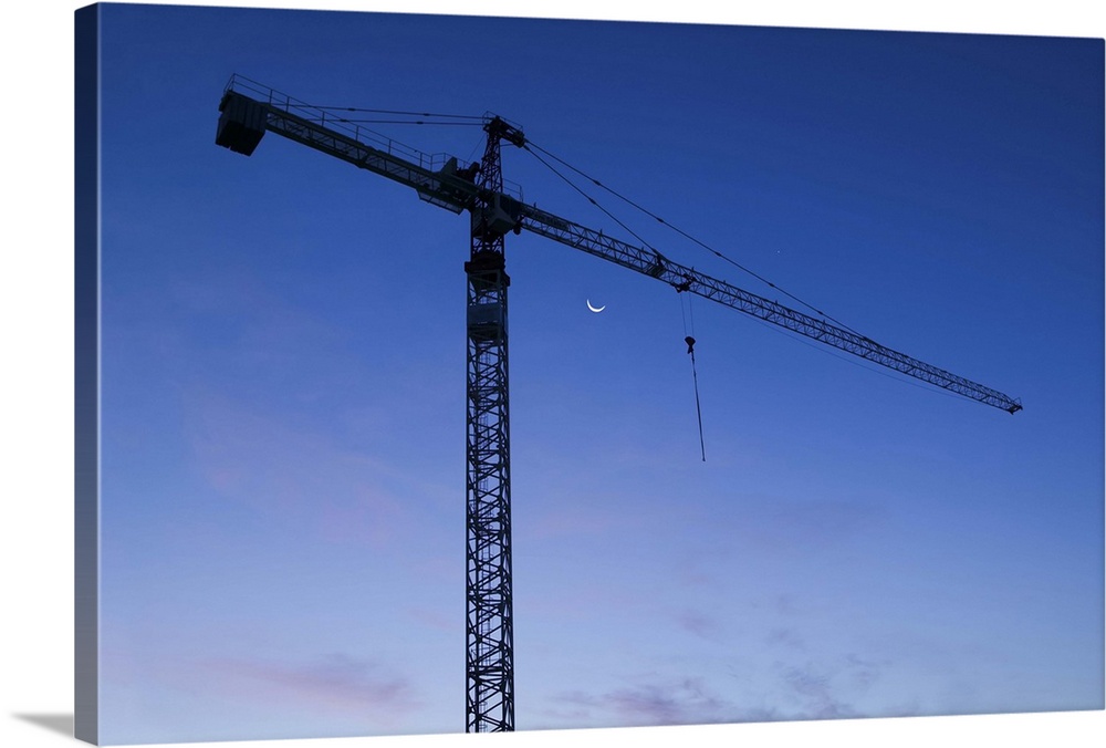 Construction crane silhouetted against a twilight sky.