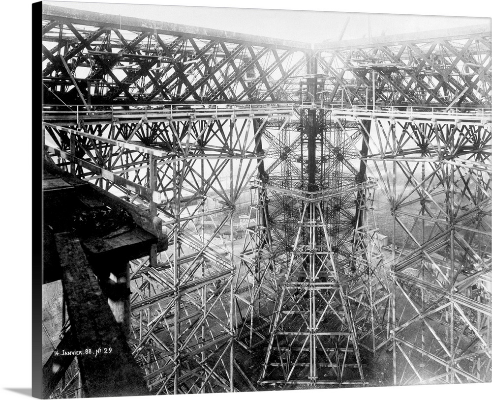 Eiffel Tower under construction. Intricate mass of ironwork at the level of the first platform with temporary supporting s...