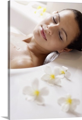 Content woman in bathtub with flowers