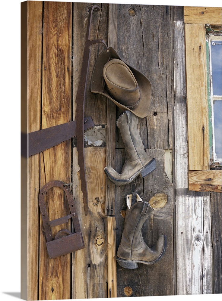 Cowboy boots and hat hanging on cabin
