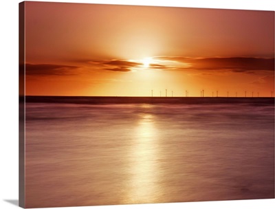 Crosby beach, golden sunset with windfarm turbines and long exposure sea.