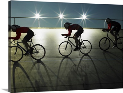 Cyclists on velodrome track at night, side view