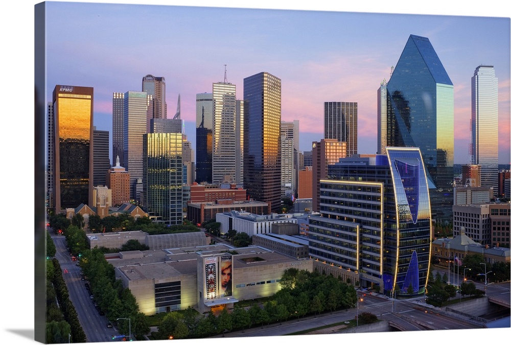 Dallas cityscape with several modern skyscrapers reflecting the fading light from the sunset at twilight.