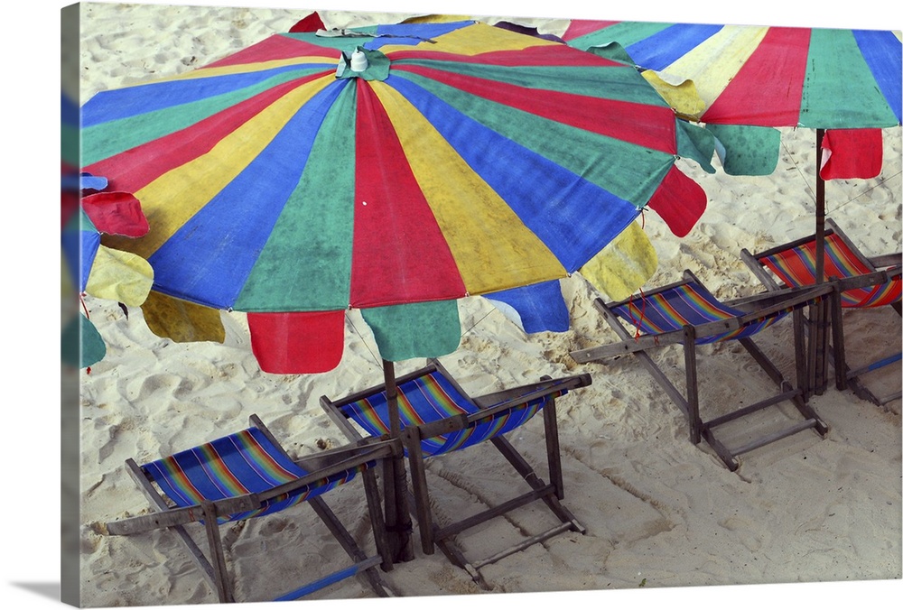 Deck chairs and bright umbrellas on Sunny beach in Thailand.