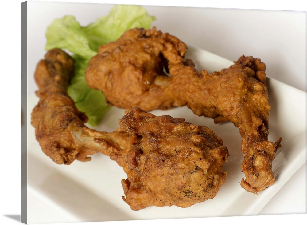 Deep fried chicken legs with lettuce served in white plate on white background.