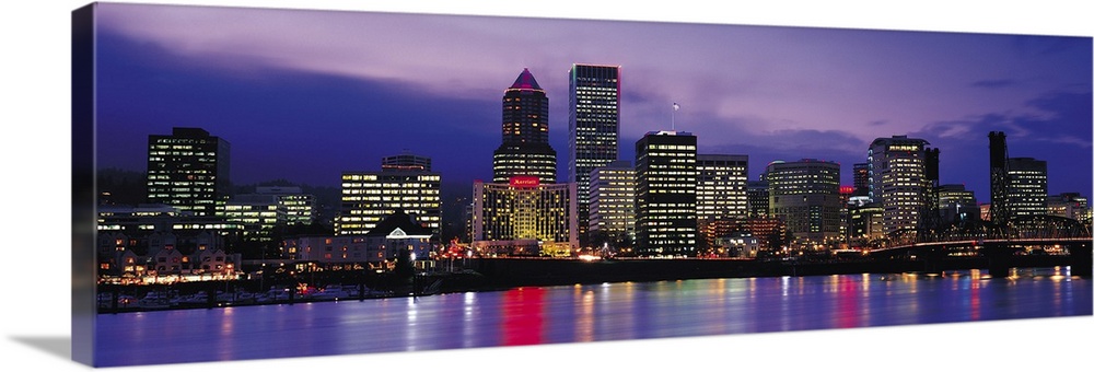 Panoramic photograph on a big canvas of brightly lit buildings of the Portland skyline, reflecting in the water in the for...