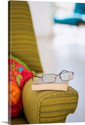 Eyeglasses and book on arm rest