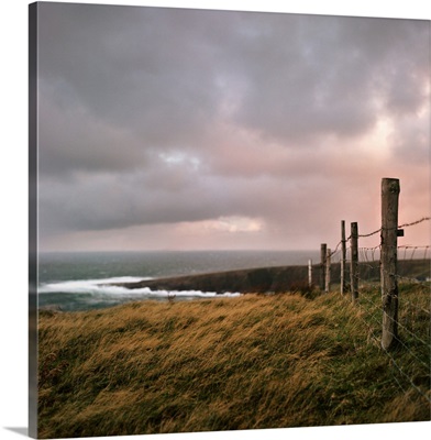 Fence stretches toward bloody foreland at sunrise in County Donegal, Ireland.