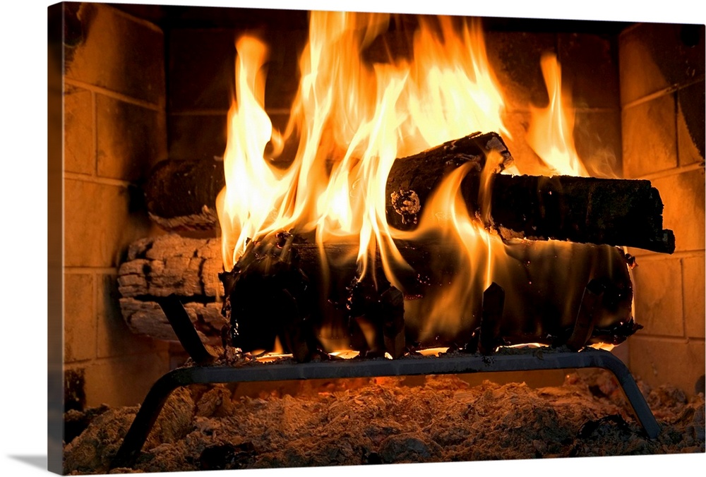 A horizontal photograph of logs burning inside a personal, home fireplace lined with bricks
