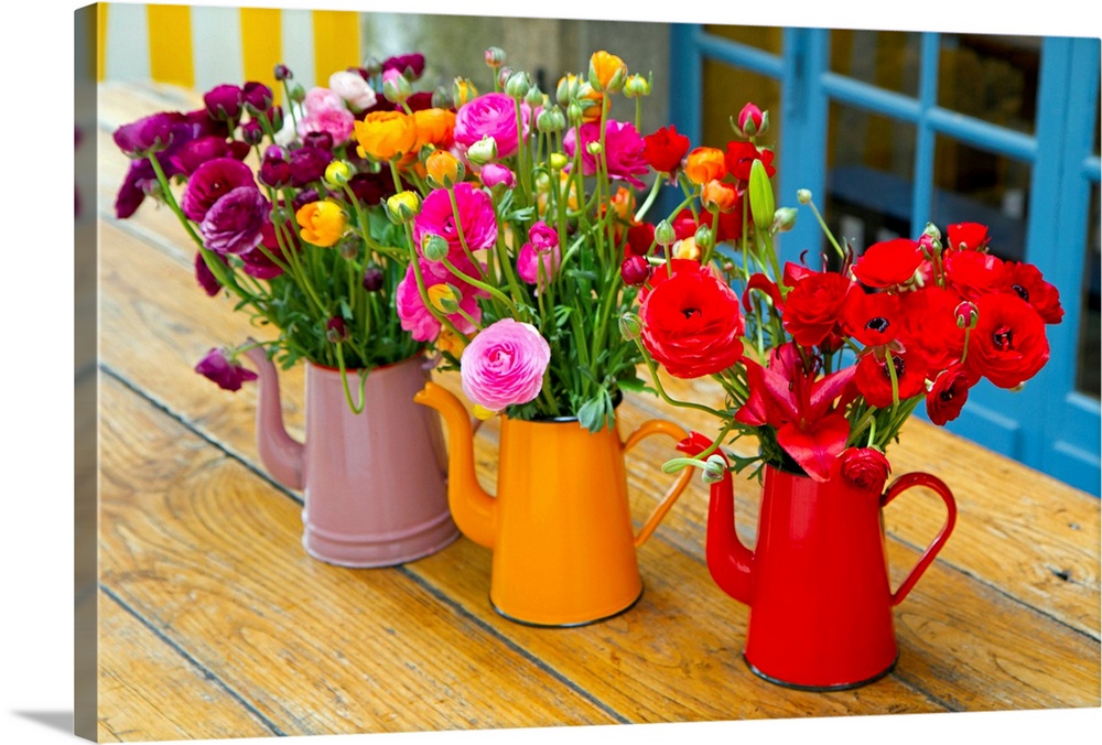Photograph of three flowerpots sitting on a table with flowers in them.