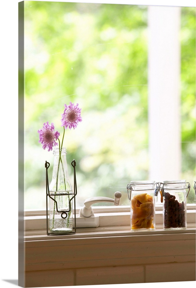 Flowers in vase and dried fruits in glass jars on windowsill