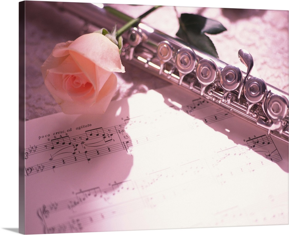 Flute next to sheet music and pink rose