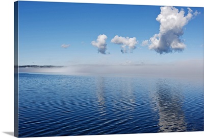 fog clearing from surface of lake to reveal blue water under blue sky