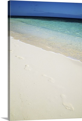 Footprints across white sandy beach