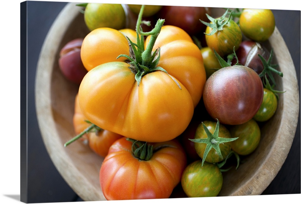 A colorful selection of heirloom tomatoes arranged in a rustic wooden bowl