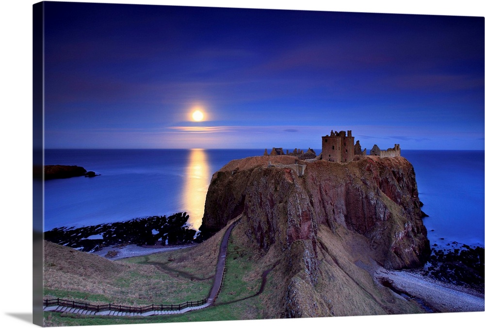 Full moon is rising over calm sea and Dunnottar castle near Stonehaven on the North East coast of Scotland on cold and fro...
