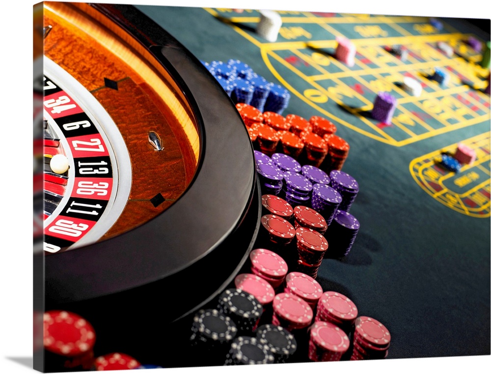 Gambling chips stacked around roulette wheel on gaming table