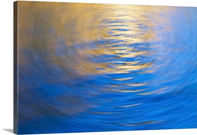 Gently rippled water reflecting gold and blue colours, vortex