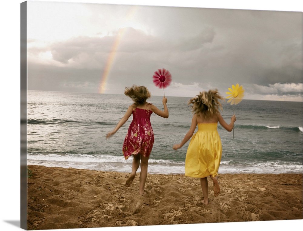 Girls running on beach holding windmills