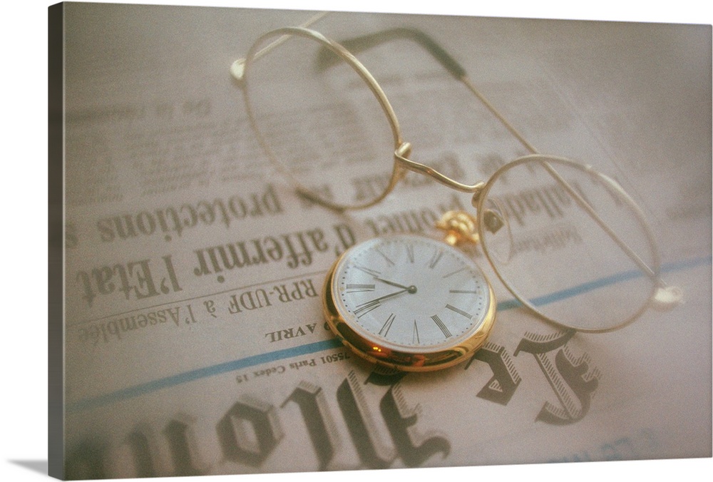 Glasses and clock on newspaper, high angle view, close up, soft focus