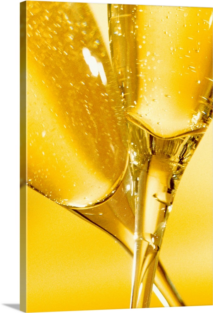 A closely taken photograph of the bottom of two champagne glasses as they touch and twist around each other.