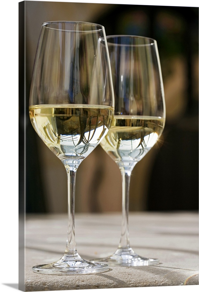 Up-close photograph of two champagne glasses half full on concrete table.