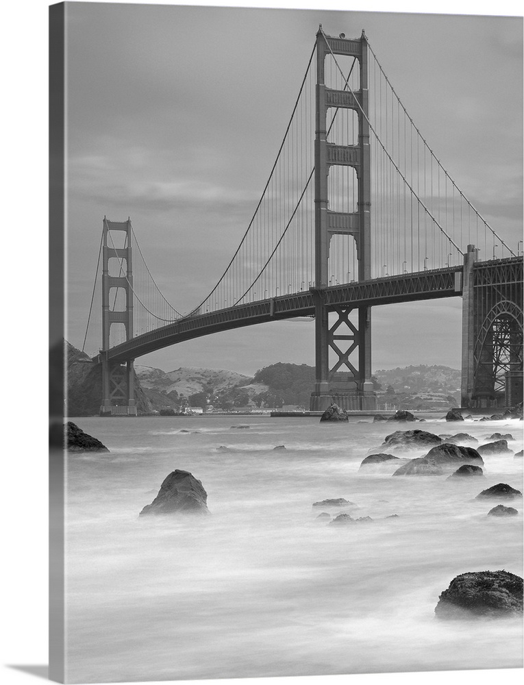 Photo on canvas of the Golden Gate Bridge with wave breaking through rocks in the water.