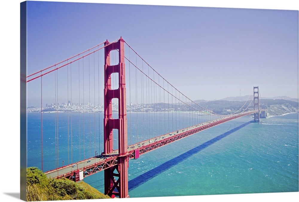 A high angle photograph is taken of the Golden Gate bridge on a bright sunny day with a soft haze over the entire picture.