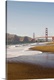 image thumbnail of Vertical photograph taken from a distance of the Golden Gate Bridge which a strip of beach and the ocean pictured in the f...