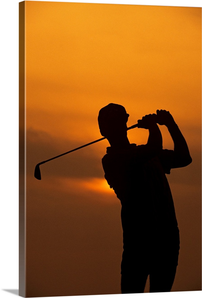 Golfer silhouetted by sunset