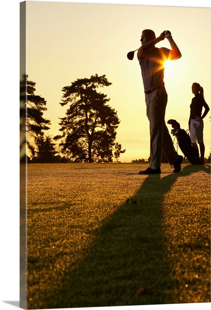 Golfers playing golf at sunset, low angle view